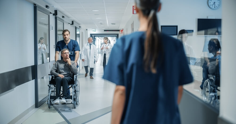 Two nurses look at each other as they walk down the hall