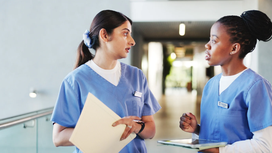 Senior nurse mentor guiding young nurse through patient chart review | Creative Health Care Insight