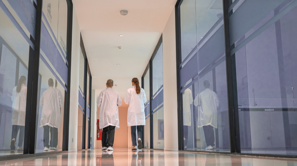 Wide Shot of a Hospital Hallway With Nursing Staff Walking Between Units During an Active Day Shift | Creative Health Care Insight